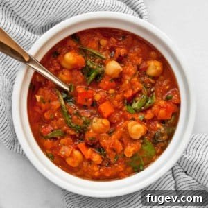 A vibrant bowl of red lentil soup with chickpeas, carrots, and spinach, ready to be enjoyed.