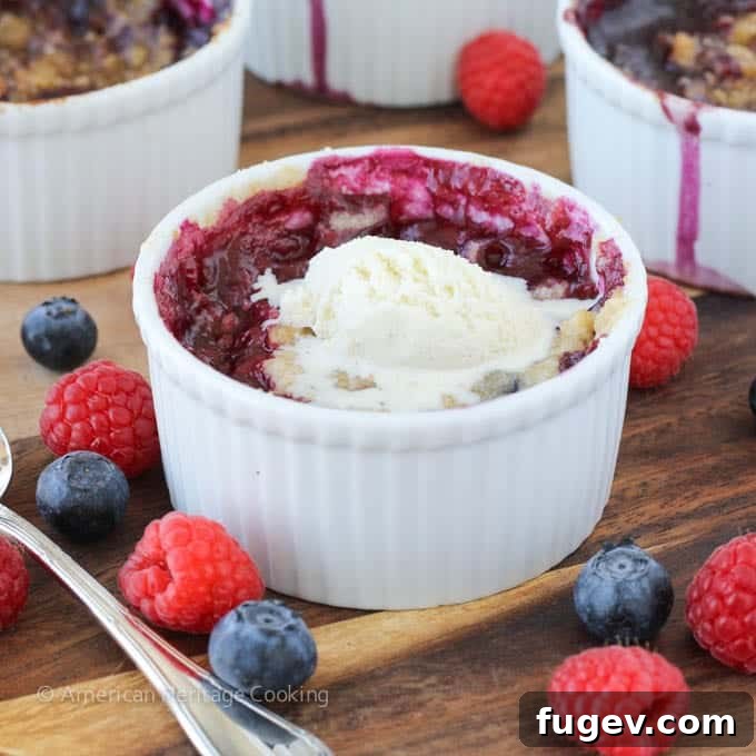 Sweet Blueberry Raspberry Crumble Cups 4 Individual blueberry and raspberry crumbles baking in ramekins, revealing bubbling fruit.