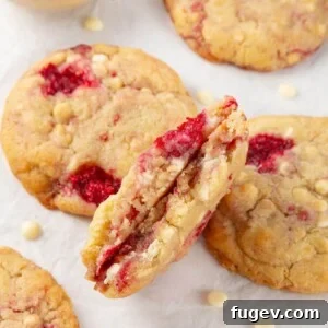 A white chocolate raspberry cookie broken in half, showing its chewy texture and gooey chocolate chips, perfect for Valentine's Day.