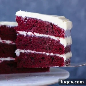 Red Velvet Layer Cake with Cream Cheese Buttercream slice on cake server, a stunning dessert.