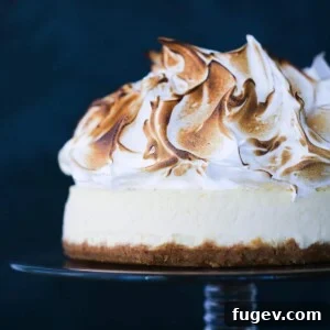 Lemon Meringue Cheesecake on a vintage glass cake stand, a beautiful and tangy dessert.