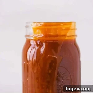 The Best Salted Caramel Sauce spilling over the side of a jar, showcasing its perfect consistency.