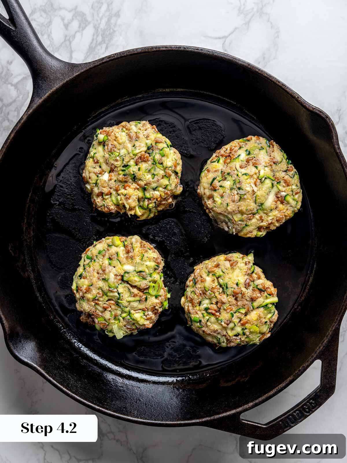 Golden Zucchini Fritters Delight 9 4 zucchini fritter patties uncooked in cast iron pan.