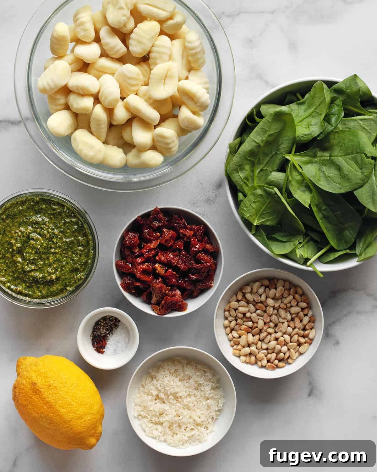 Tuscan Gnocchi with Sun-Dried Tomato Pesto 3 A flat lay photograph of all the ingredients needed for pesto gnocchi, including gnocchi, pesto, sun-dried tomatoes, spinach, pine nuts, Parmesan, and a lemon.