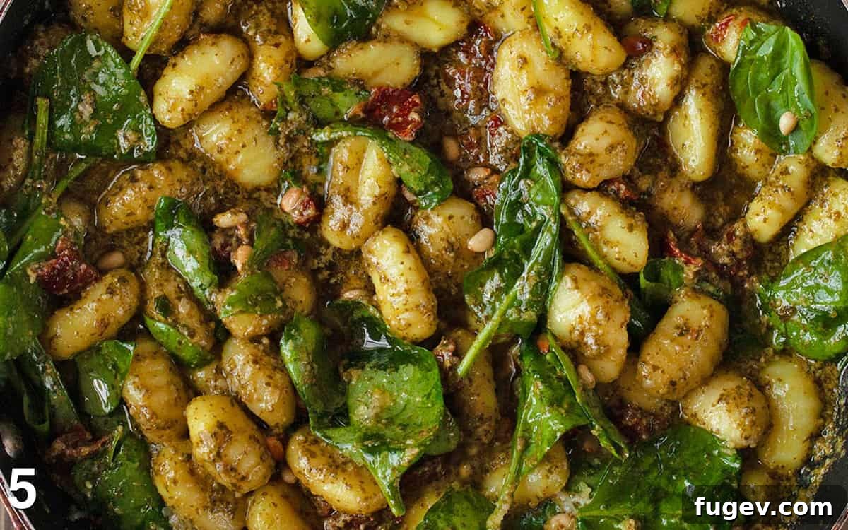 Tuscan Gnocchi with Sun-Dried Tomato Pesto 6 A close-up of the finished pesto gnocchi with sun-dried tomatoes and spinach, simmering in a rich pesto and fresh lemon juice sauce in a large skillet, ready to serve.