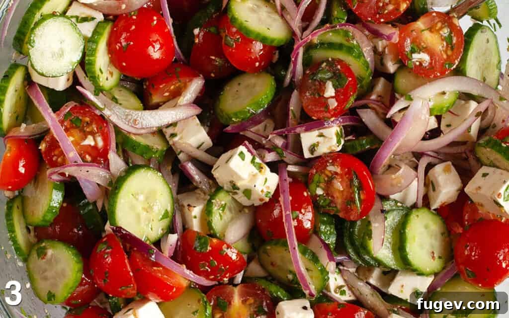 Mediterranean Feta Salad 5 Close-up image of salad ingredients and vinaigrette stirred together.