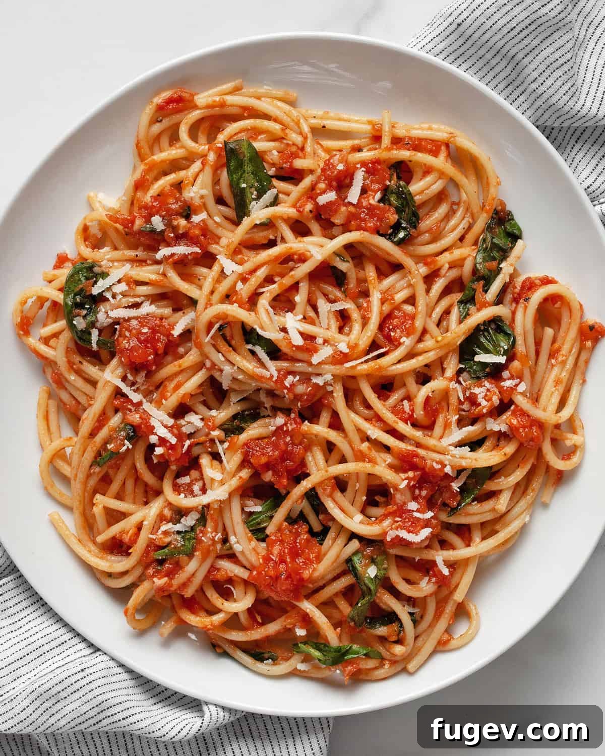 Garden Fresh Tomato Basil Delight 7 A close-up of a plate of fresh tomato basil pasta, garnished with a sprig of fresh basil, showing the rich red sauce clinging to the spaghetti noodles.