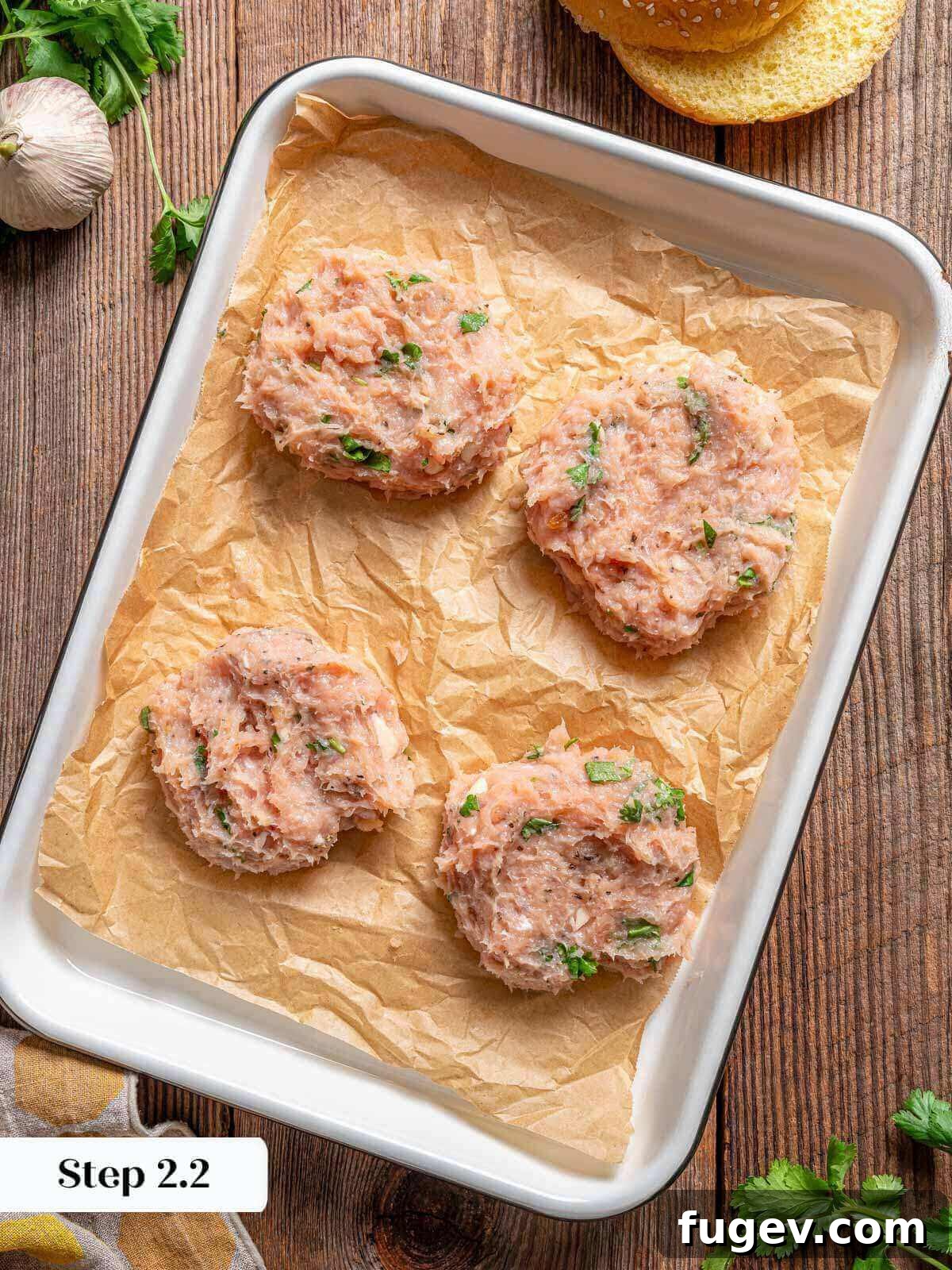 Succulent Chicken Burgers 6 Four perfectly shaped ground chicken patties resting on parchment paper, ready for grilling.