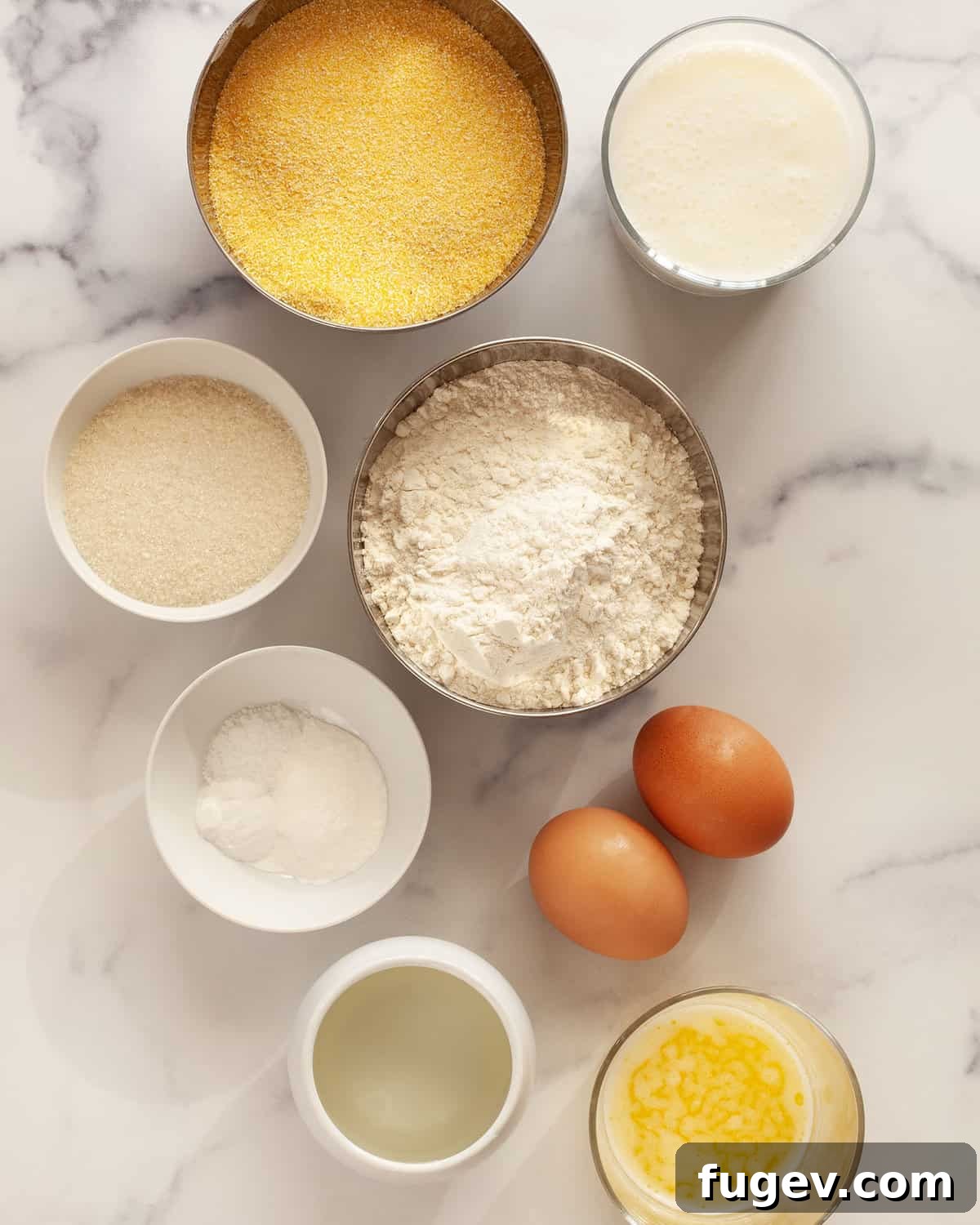 Southern Comfort Buttermilk Cornbread 3 A flat lay of all the essential ingredients for buttermilk cornbread, including cornmeal, flour, sugar, eggs, salt, baking powder, baking soda, oil, buttermilk, and melted butter, neatly arranged on a counter.