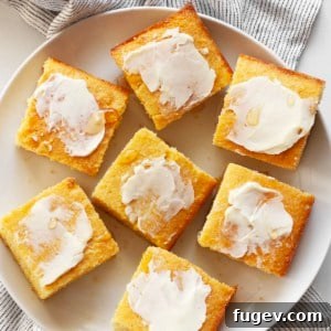 Golden brown cornbread cut into perfect squares, with some pieces glistening with melted butter and a drizzle of honey.