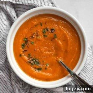 Velvety Roasted Carrot Bisque 7 A vibrant bowl of roasted carrot soup, garnished with fresh green parsley and a sprinkle of black pepper, served warm.