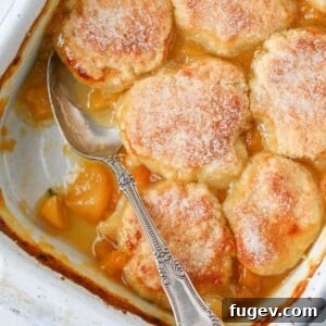 Old Fashioned Peach Cobbler, baked and being served with a vintage spoon
