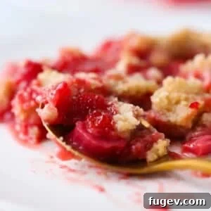 Close-up of juicy strawberries and rhubarb baked under a golden crumble topping