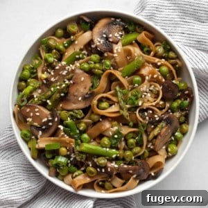 Vibrant Asparagus, Mushroom and Pea Stir-Fry 8 A bowl of hot udon noodle stir-fry with asparagus, mushrooms, and peas, ready to be enjoyed.