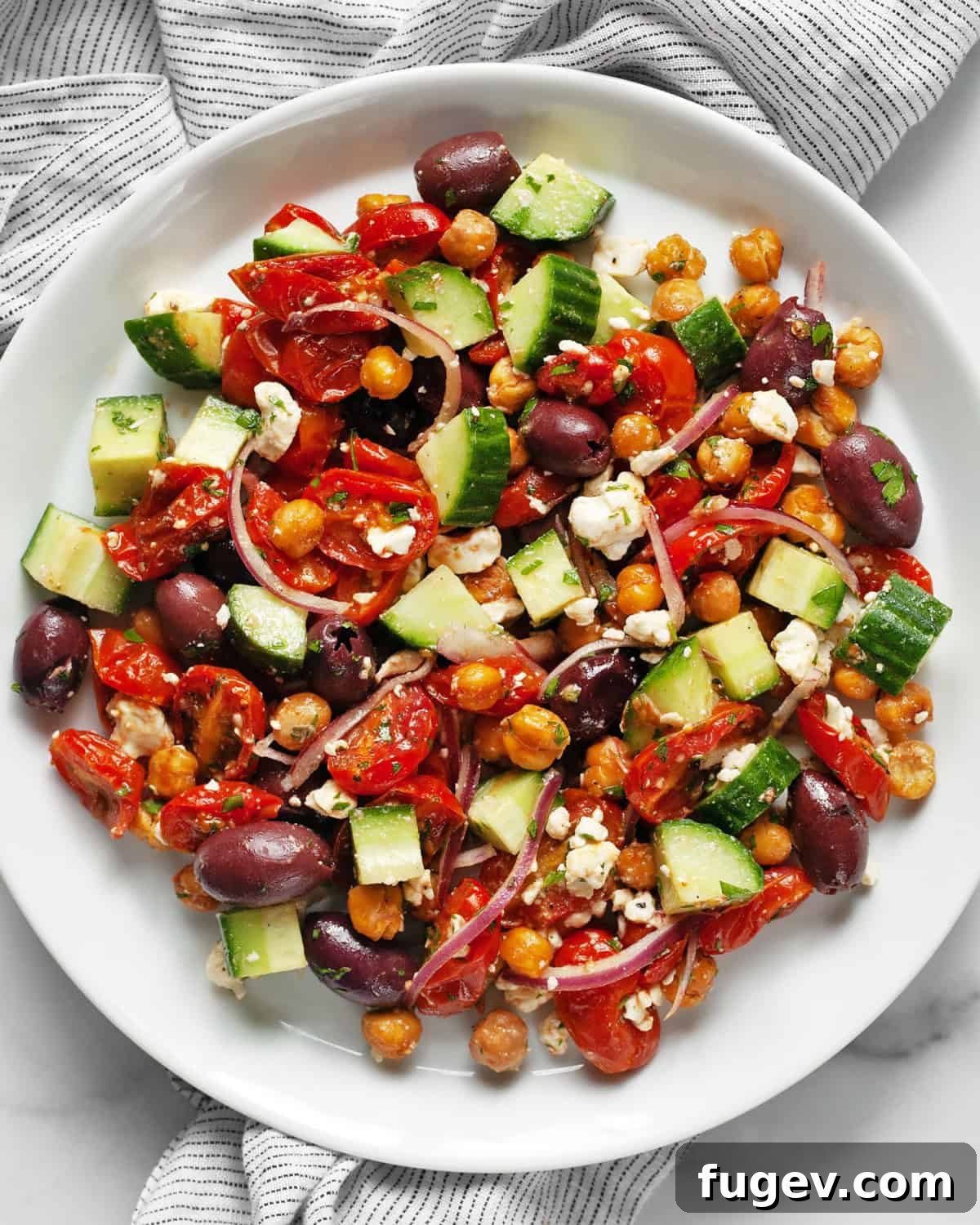 Mediterranean Chickpea Salad 2 Vibrant roasted Greek chickpea salad with tomatoes, chickpeas, cucumbers, olives, and feta in a bowl.