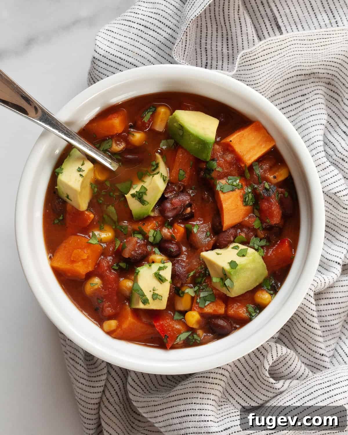 Hearty Sweet Potato Black Bean Chili 2 A beautifully presented bowl of sweet potato black bean chili, garnished with fresh cilantro and a dollop of sour cream or vegan cream, ready to be enjoyed.