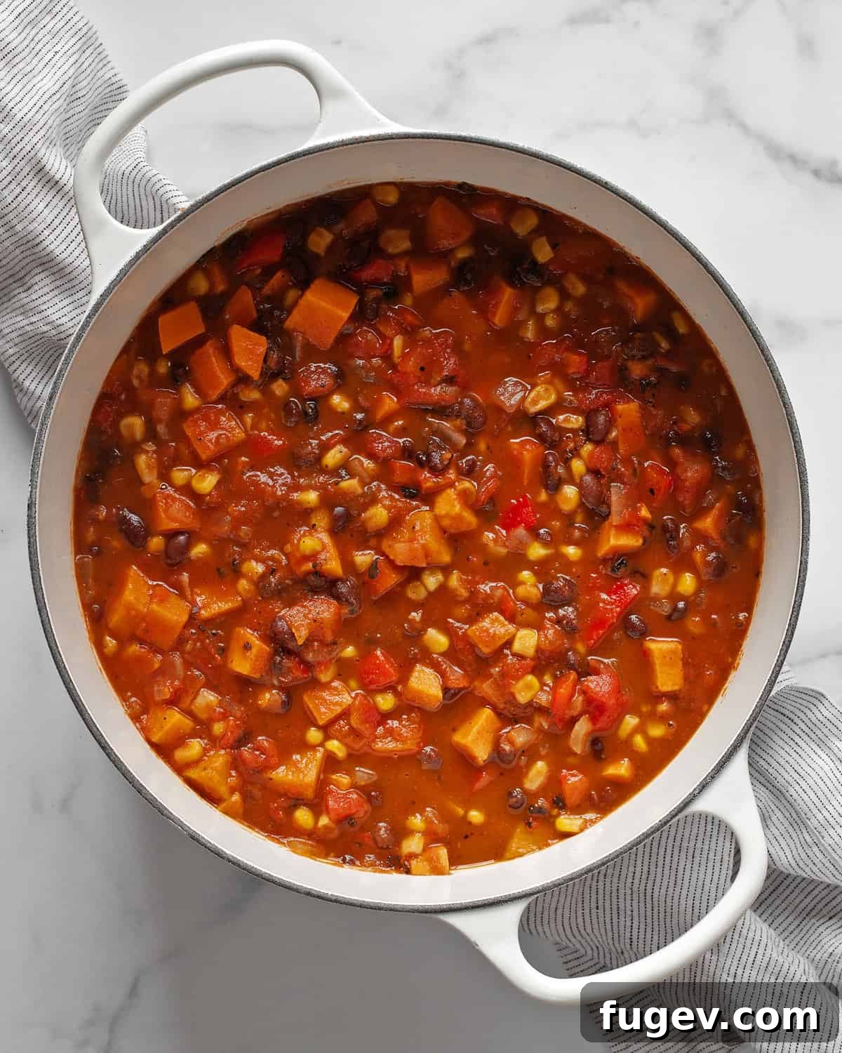 Hearty Sweet Potato Black Bean Chili 6 A large, steaming pot of rich vegetarian chili, brimming with chunky sweet potatoes, black beans, corn, and bell peppers, ready to be ladled into bowls.