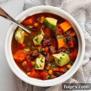 A vibrant bowl of vegan sweet potato chili, rich in color and texture, topped with fresh cilantro.