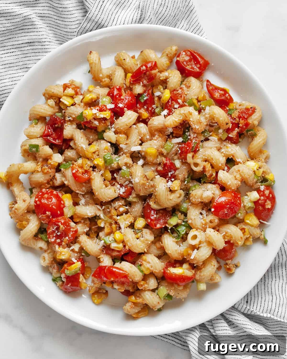 Golden Corn Pesto Pasta 2 A beautifully plated dish of sweet corn pesto pasta, showcasing the vibrant colors of roasted corn, cherry tomatoes, and fresh scallions.