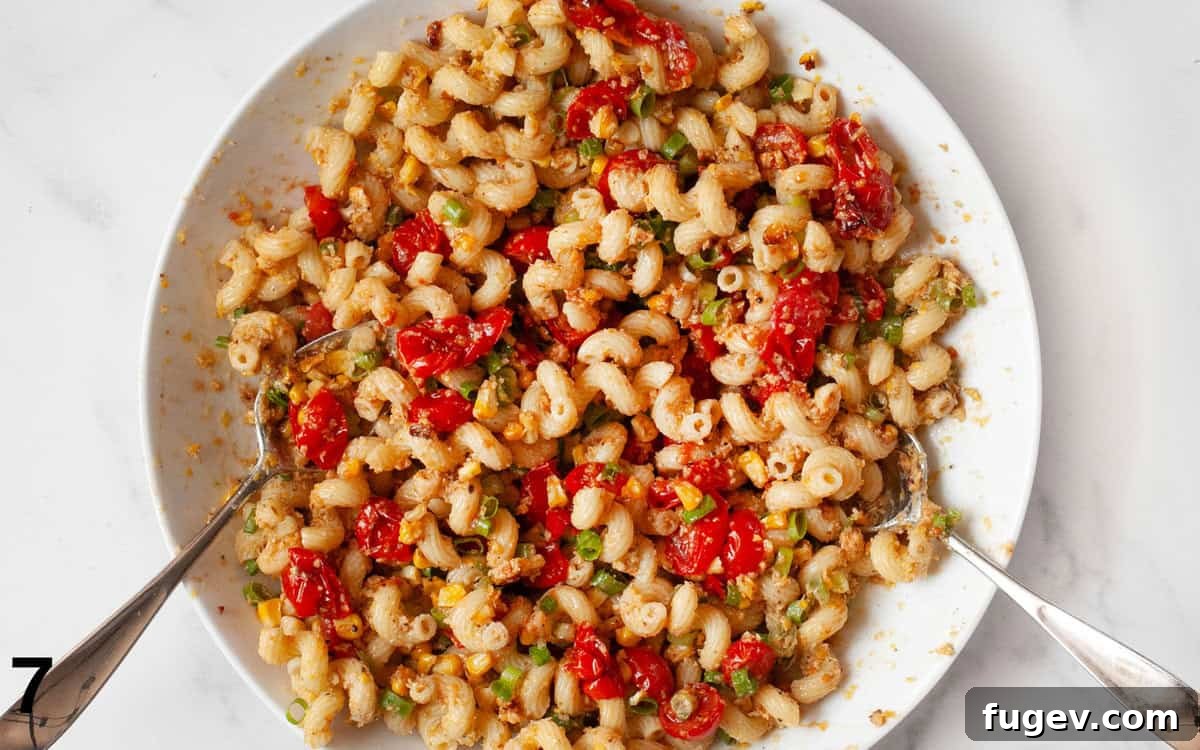 Golden Corn Pesto Pasta 7 A large mixing bowl filled with the finished sweet corn pesto pasta, showing the roasted corn, tomatoes, and green scallions mixed throughout.