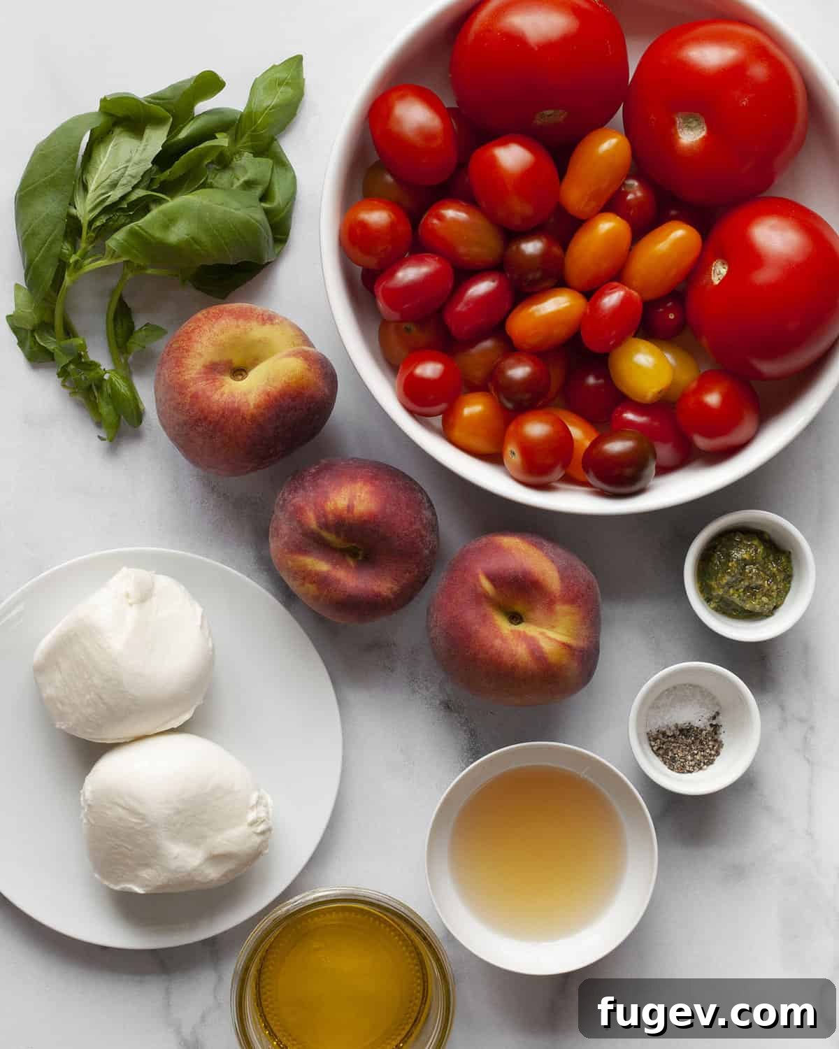 Summer Peach Caprese Salad 3 Ingredients including tomatoes, peaches, mozzarella, basil, olive oil, vinegar, pesto, salt and pepper. Arranged neatly on a cutting board, showcasing their vibrant colors and freshness.