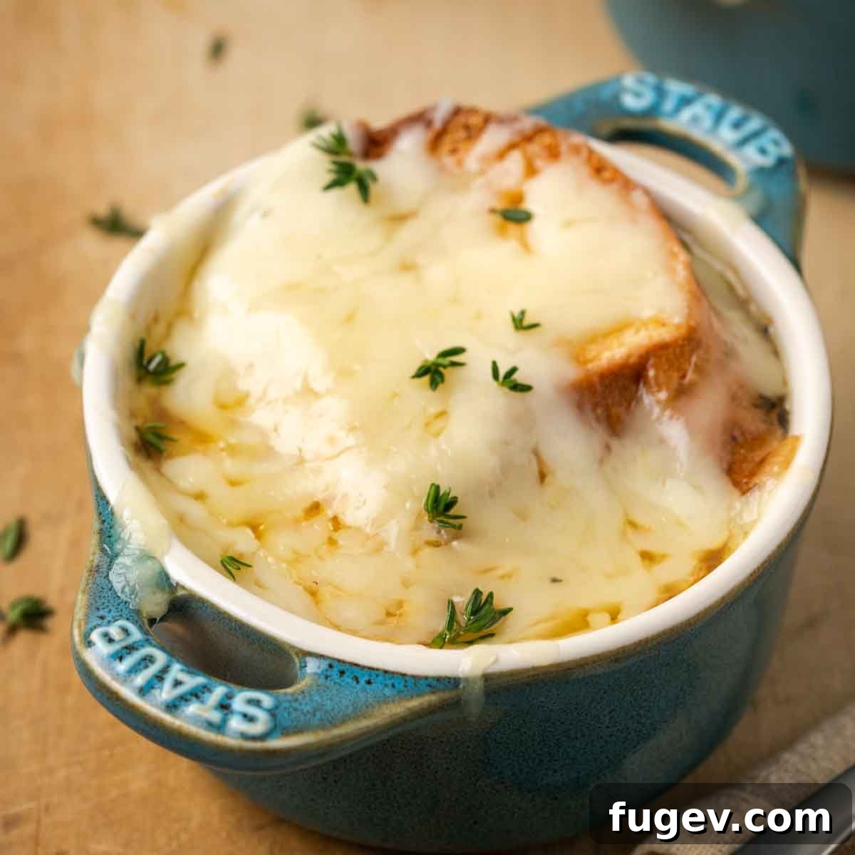 The Quintessential French Onion 3 melted cheese on top of small staub baking dish.