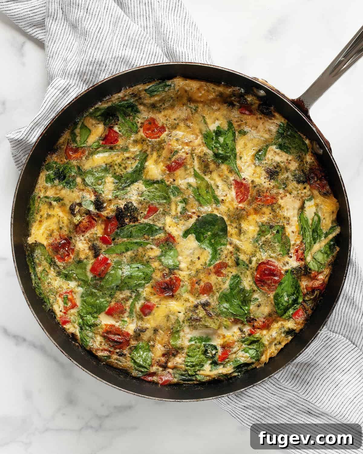 Vibrant Roasted Vegetable Egg White Frittata 2 A beautifully cooked egg white frittata with roasted bell peppers, tomatoes, and broccoli, presented in a cast-iron skillet, ready to be served.