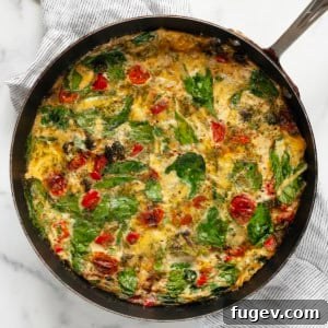 Roasted vegetable frittata in a skillet, showcasing a golden-brown top and colorful vegetable fillings.