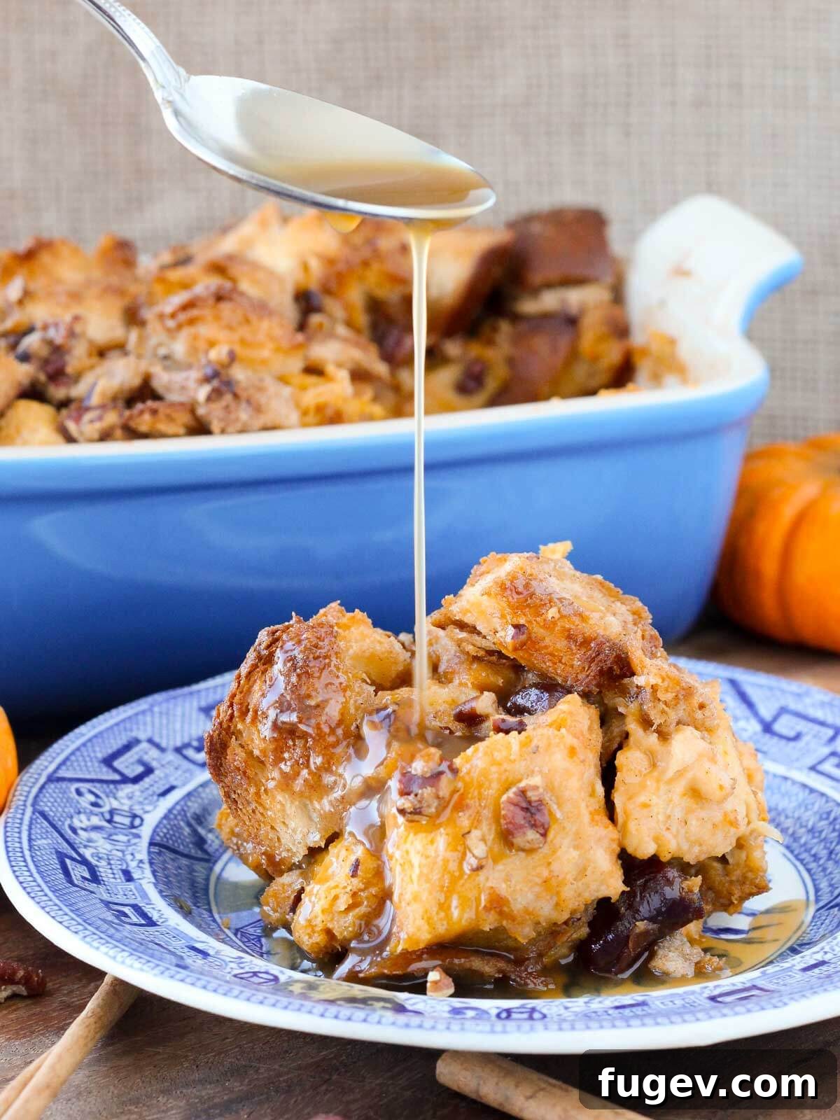 Cozy Pumpkin Bread Pudding 2 Pumpkin bread pudding with rich maple bourbon sauce being poured over it, highlighting its moist texture.