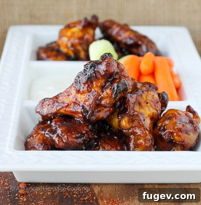 Sticky Sweet Chili Baked Wings 4 Plated chicken wings arranged neatly with a side of fresh carrot sticks on a white plate, ready to be enjoyed.