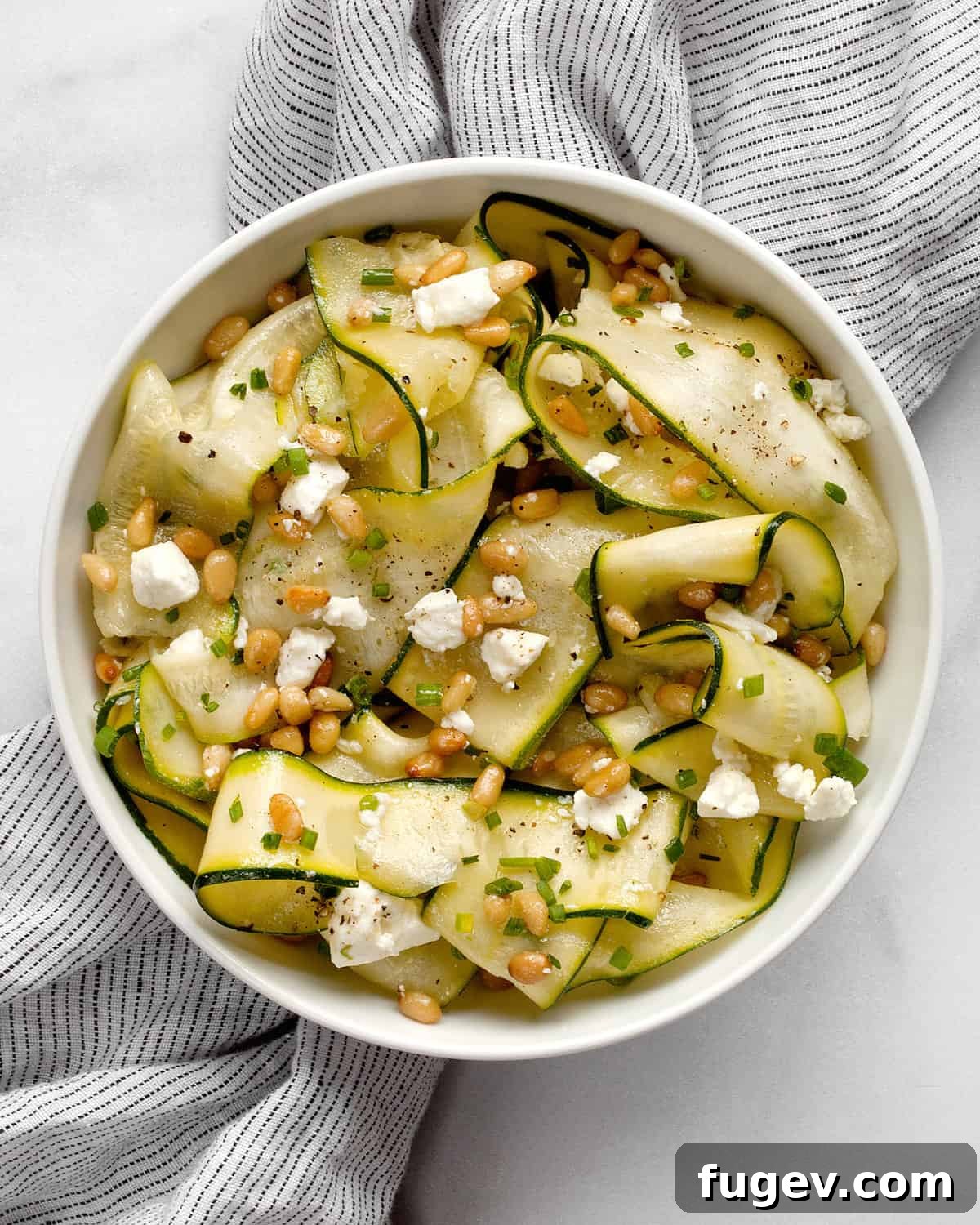 Zesty Zucchini Salad with Feta and Pine Nuts 6 Close-up of a fresh zucchini ribbon salad in a serving bowl, ready to be enjoyed.