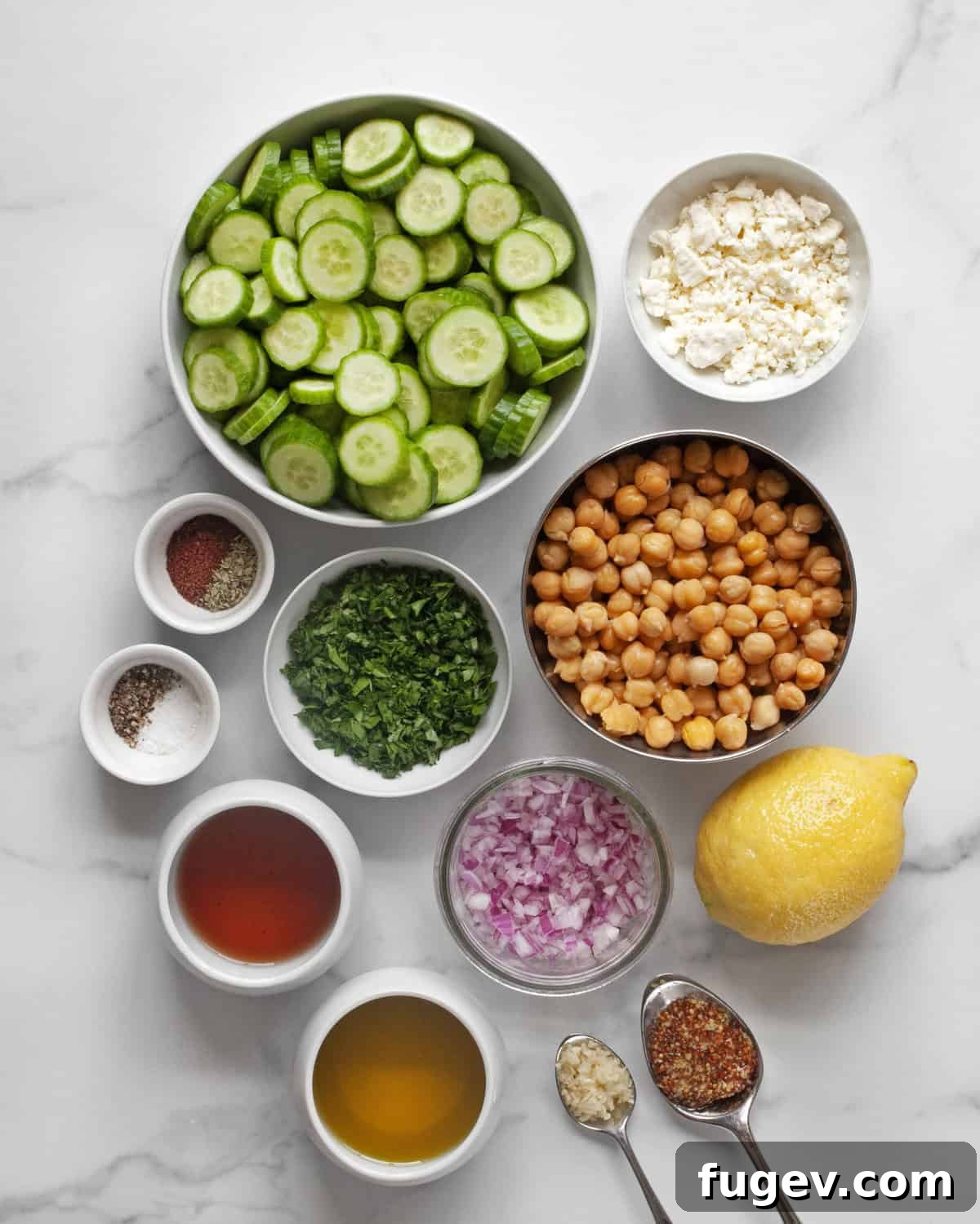 Mediterranean Chickpea Cucumber Refresh 3 A flat lay photograph of all the ingredients for the chickpea cucumber salad: cucumbers, chickpeas, feta, parsley, lemon, red onions, olive oil, red wine vinegar, and various spices.