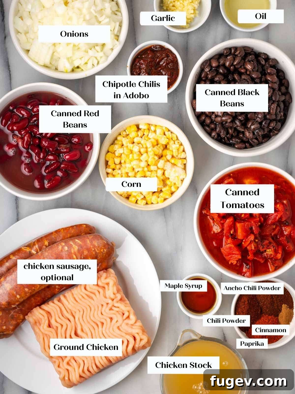 Smoldering Chipotle Chili 3 A curated selection of fresh and canned ingredients for making chicken chili, laid out on a clean white marble surface, ready for preparation.