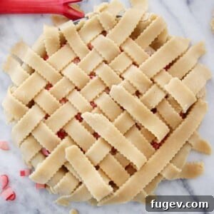 The Art of the Perfect Pie Lattice 15 Close-up of a beautifully baked lattice pie crust on a strawberry rhubarb pie, showcasing the golden-brown woven design.