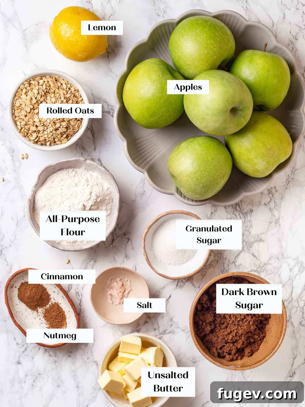 Effortless Apple Crisp Perfection 4 All the essential ingredients for an apple crisp laid out on a marble counter, including fresh apples, cinnamon, sugar, butter, and rolled oats.