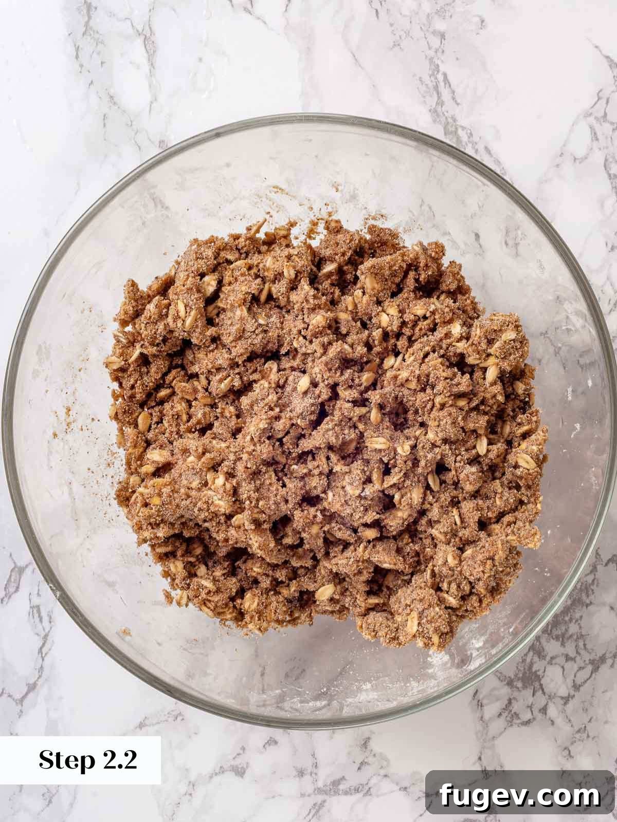 Effortless Apple Crisp Perfection 7 The mixed apple crisp topping, showing crumbly butter and oat mixture in a bowl, after being worked by hand.