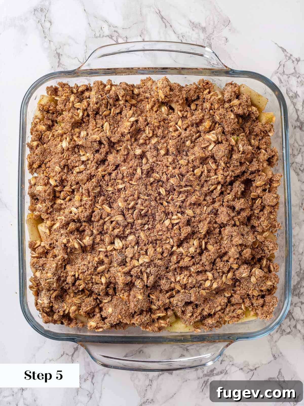 Effortless Apple Crisp Perfection 8 Unbaked apple crisp assembled in a baking dish, with the streusel topping spread evenly over the apple filling, ready for the oven.