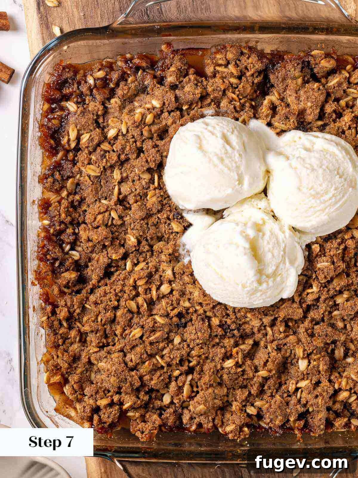 Effortless Apple Crisp Perfection 9 Baked apple crisp in a baking dish, golden brown with bubbling filling, and a scoop of vanilla ice cream melting on top.