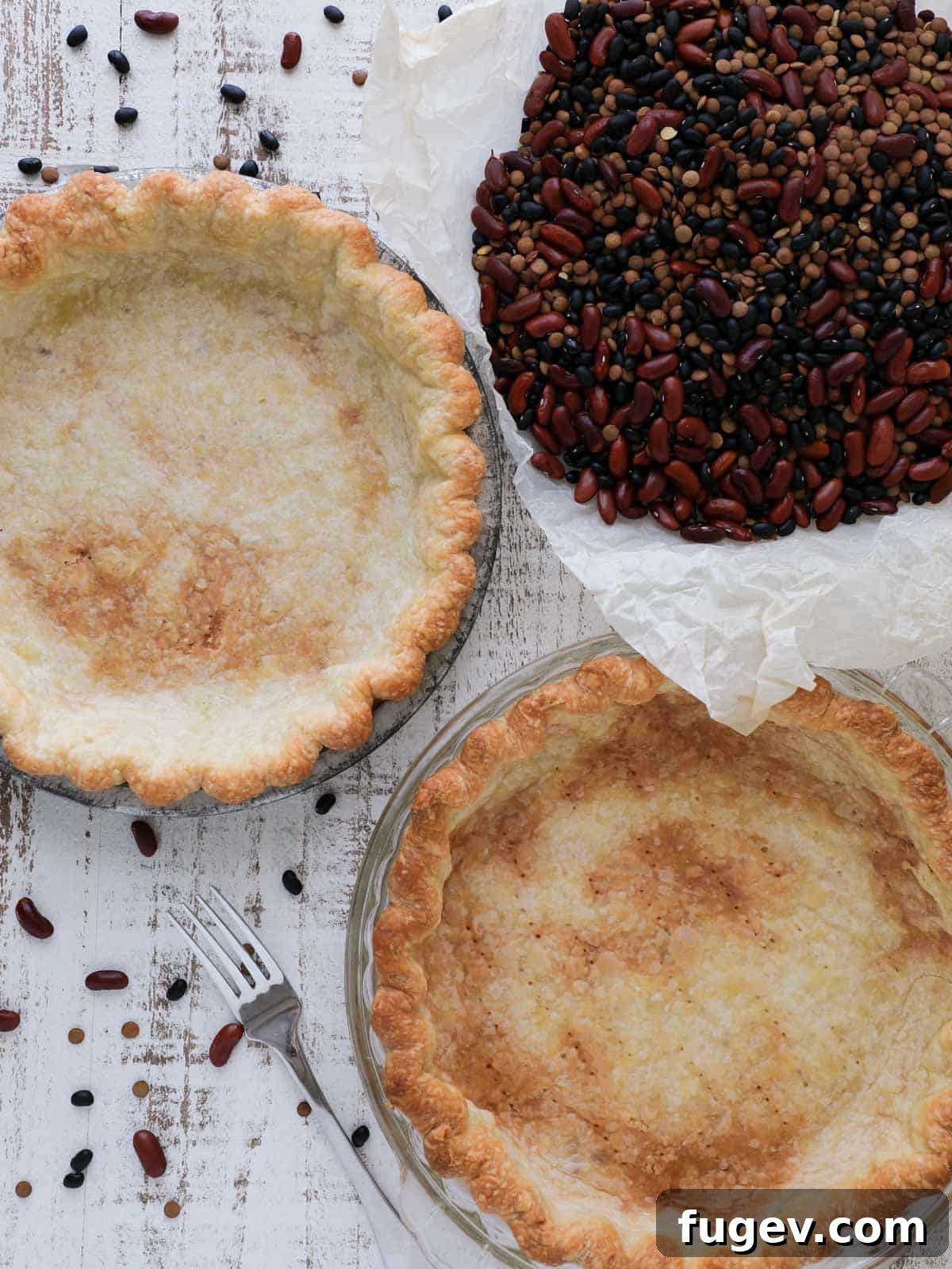 Pre-Bake Perfection: A Guide to Crisp Pie Crusts 2 Two perfectly blind-baked pie crusts resting on a clean white wooden surface, with scattered baking beans illustrating the process.