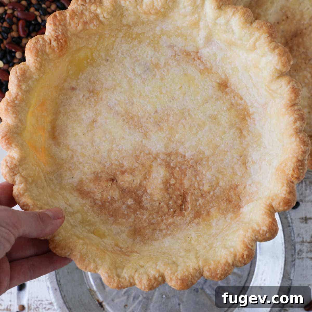 Pre-Bake Perfection: A Guide to Crisp Pie Crusts 13 A hand gently holding a beautifully par-baked pie crust, showcasing its ideal golden-brown interior texture.