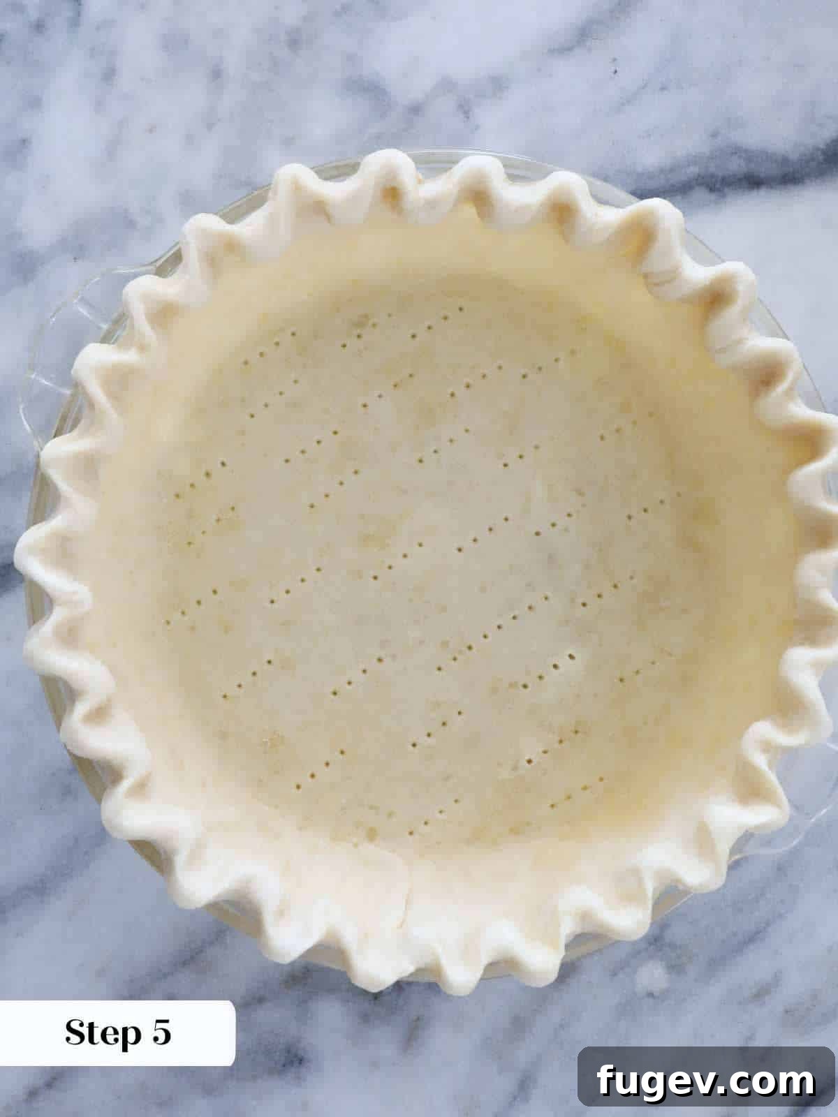 Pre-Bake Perfection: A Guide to Crisp Pie Crusts 7 A perfectly lined, fluted, and docked unbaked pie crust gracefully resting in a metal pie tin, showcasing careful preparation.