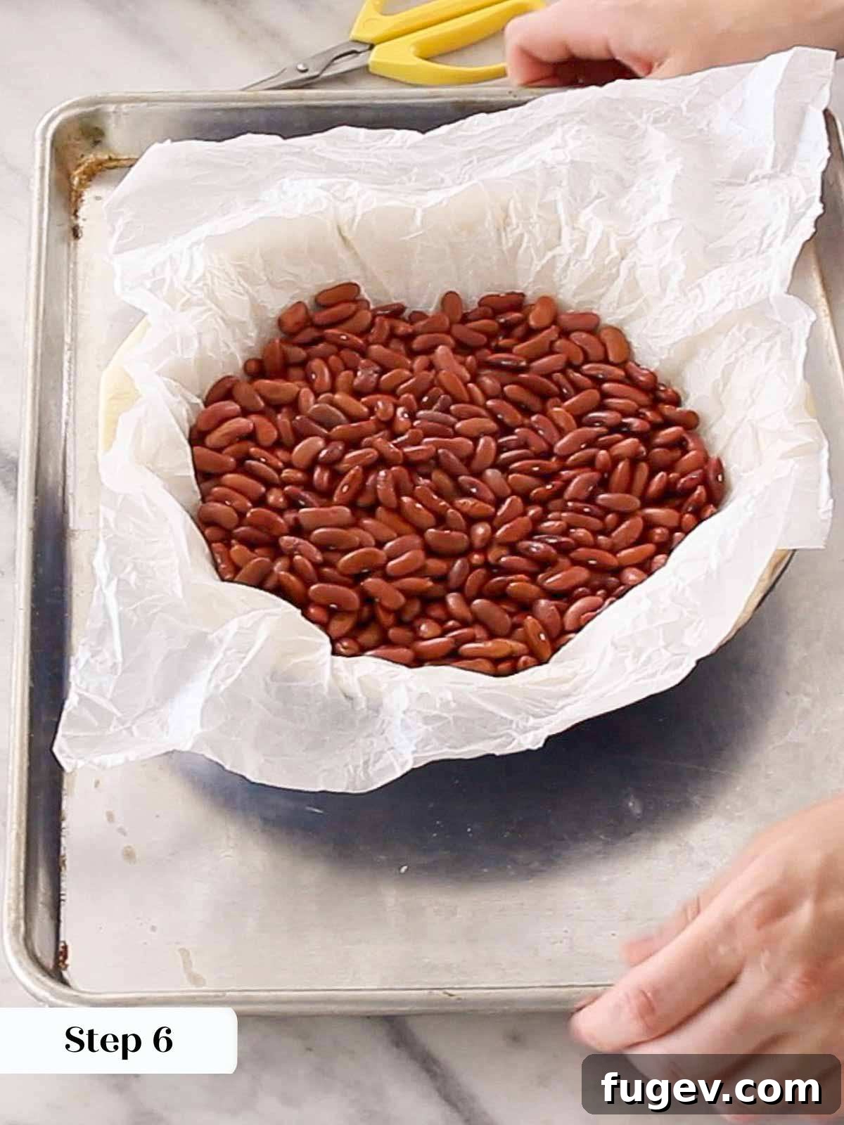 Pre-Bake Perfection: A Guide to Crisp Pie Crusts 8 Parchment paper filled with baking beans neatly resting in a par-baked pie crust, showing initial browning.