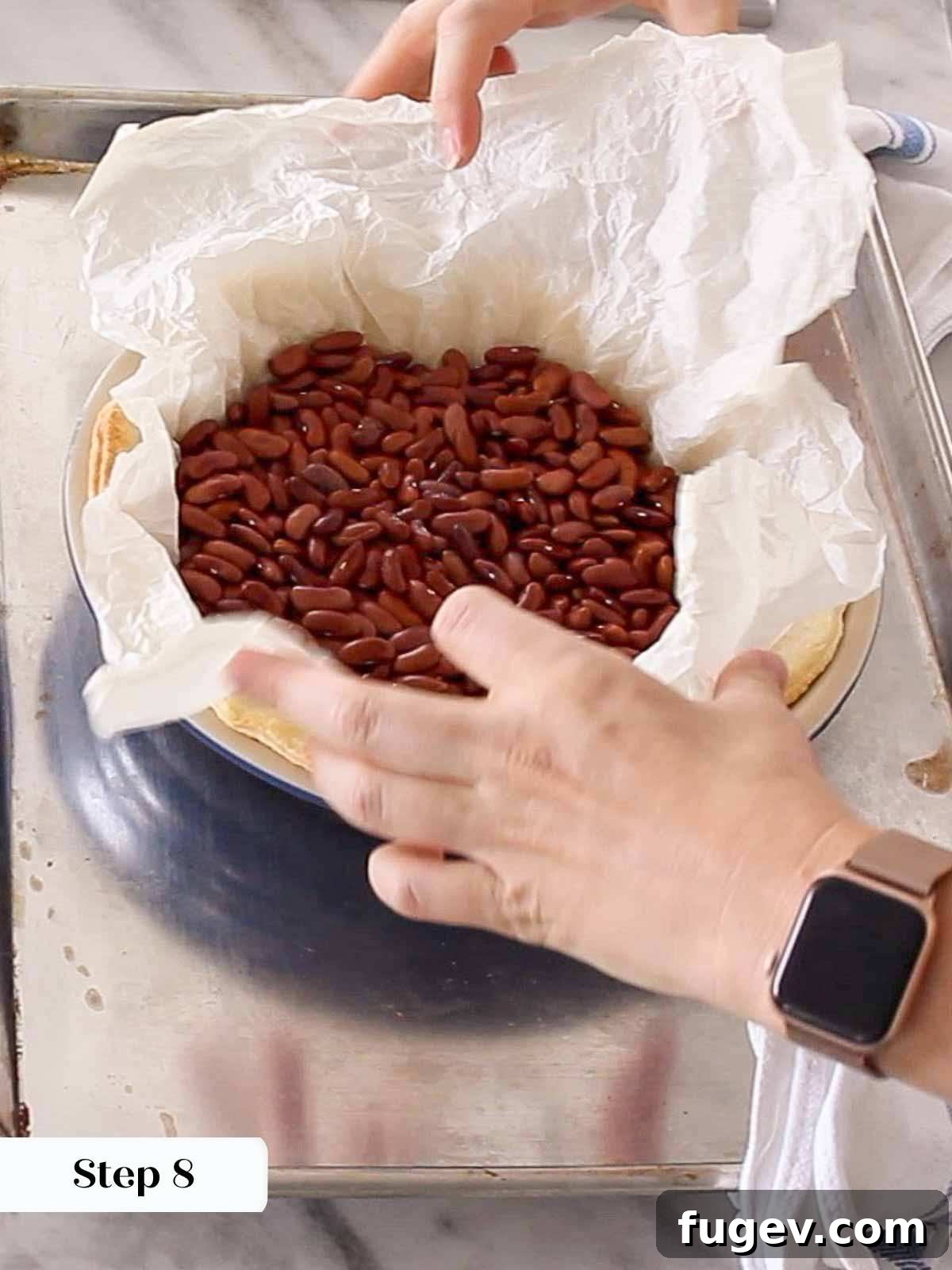 Pre-Bake Perfection: A Guide to Crisp Pie Crusts 9 A hand carefully and gently removing pie weights and parchment paper from a partially blind-baked crust.