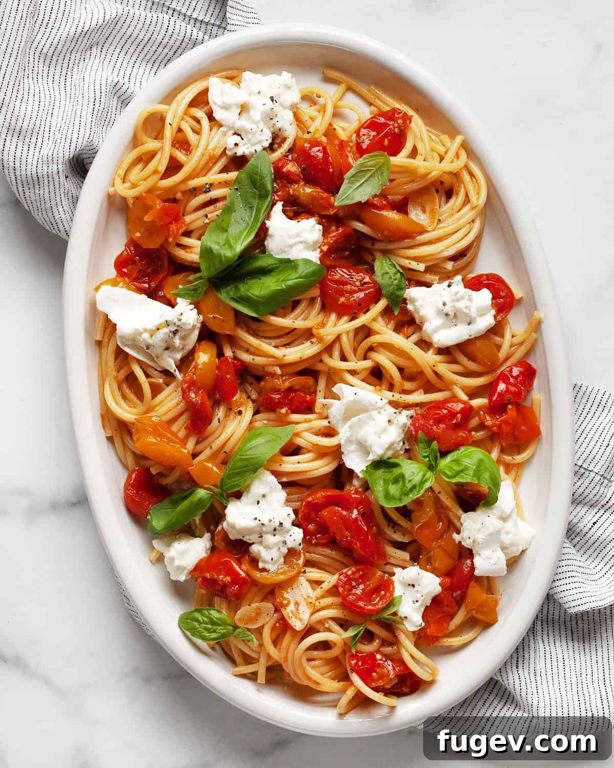Creamy Burrata & Charred Tomato Pasta 2 A vibrant serving of roasted tomato burrata pasta garnished with fresh basil on an oval platter.