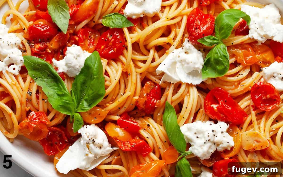 Creamy Burrata & Charred Tomato Pasta 6 A close-up of finished pasta with roasted tomatoes, creamy burrata, and fresh basil on a white serving plate, ready to be enjoyed.