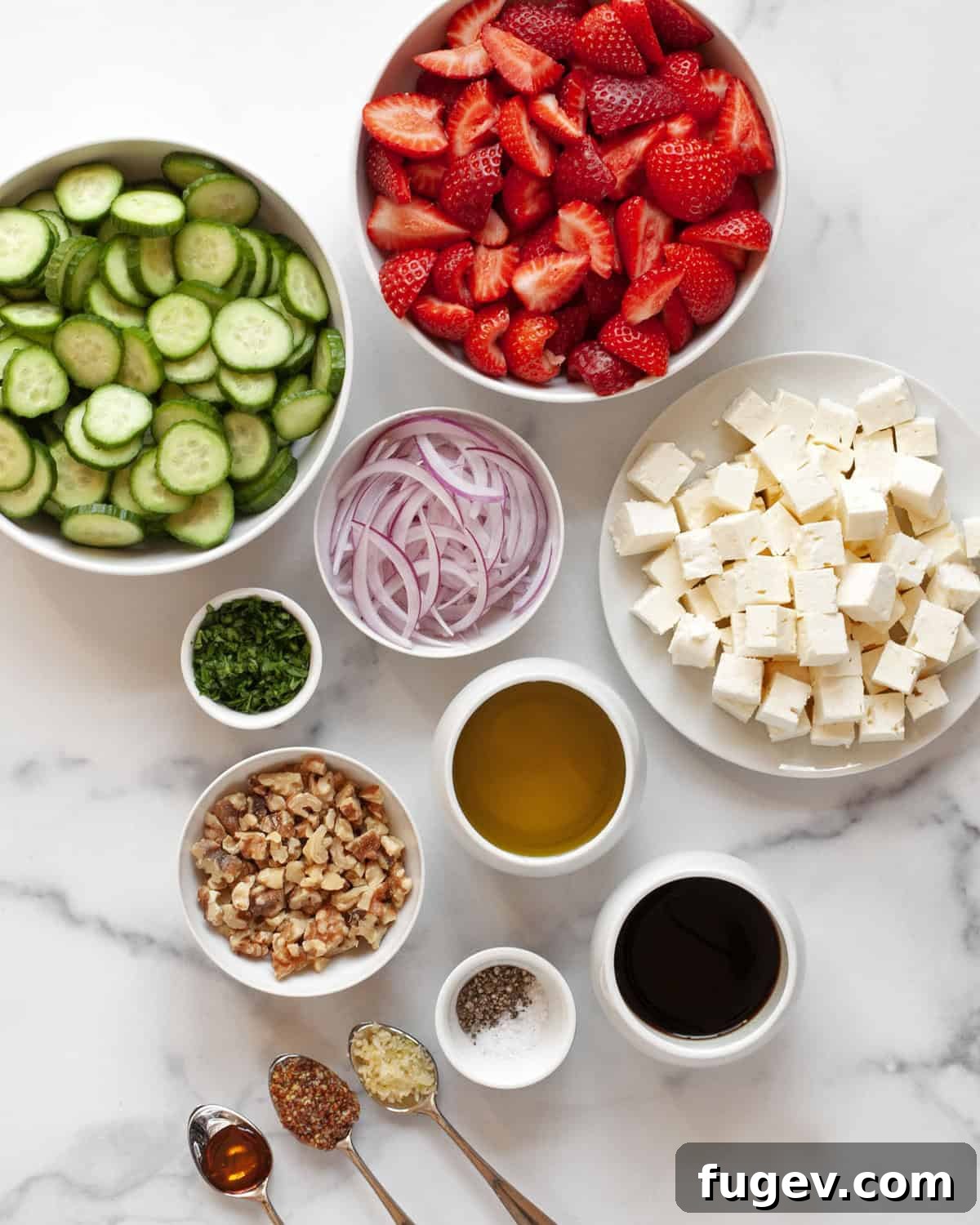 Strawberry Feta Sparkle 3 A beautifully arranged flat lay of all the fresh ingredients required to make the strawberry feta salad: vibrant red strawberries, crisp green Persian cucumbers, a block of creamy feta cheese, thin slices of red onion, toasted walnuts, fresh parsley, and individual containers of balsamic vinegar, olive oil, honey, garlic, and whole grain mustard.
