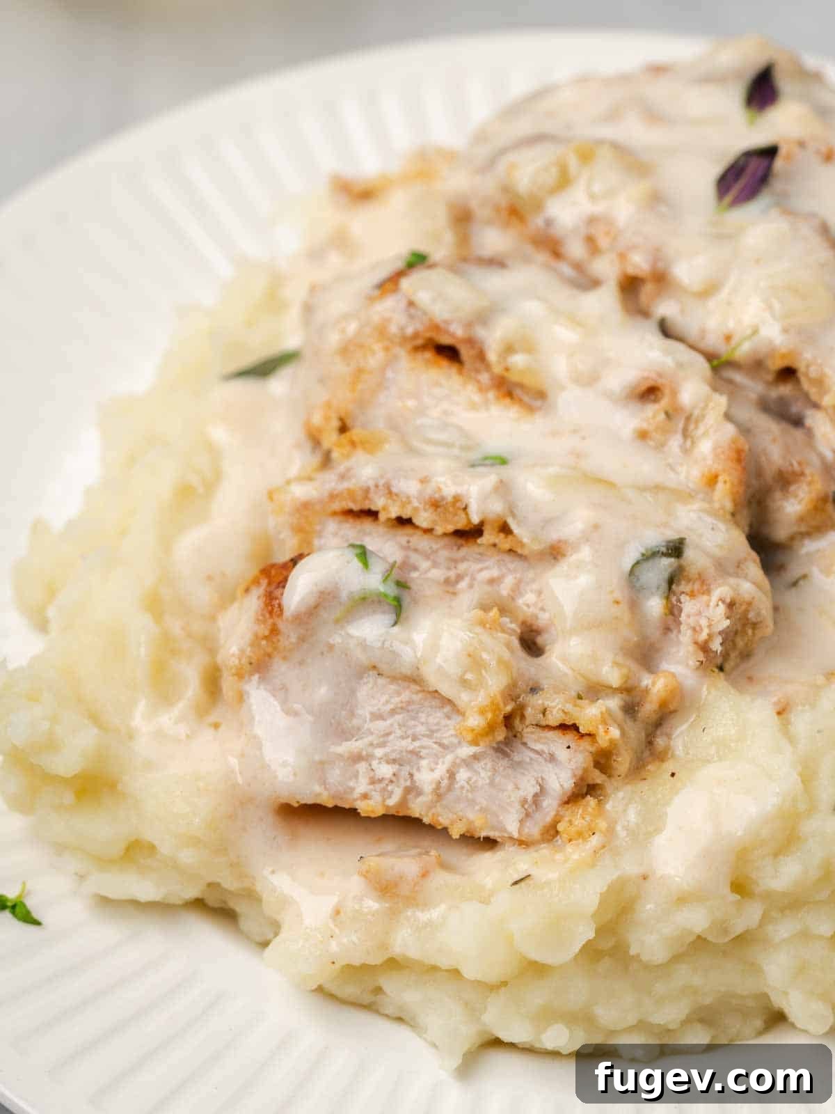 Creamy Mushroom Pork Chops 5 Sliced baked pork chop served on a bed of creamy mashed potatoes with a generous amount of mushroom sauce.