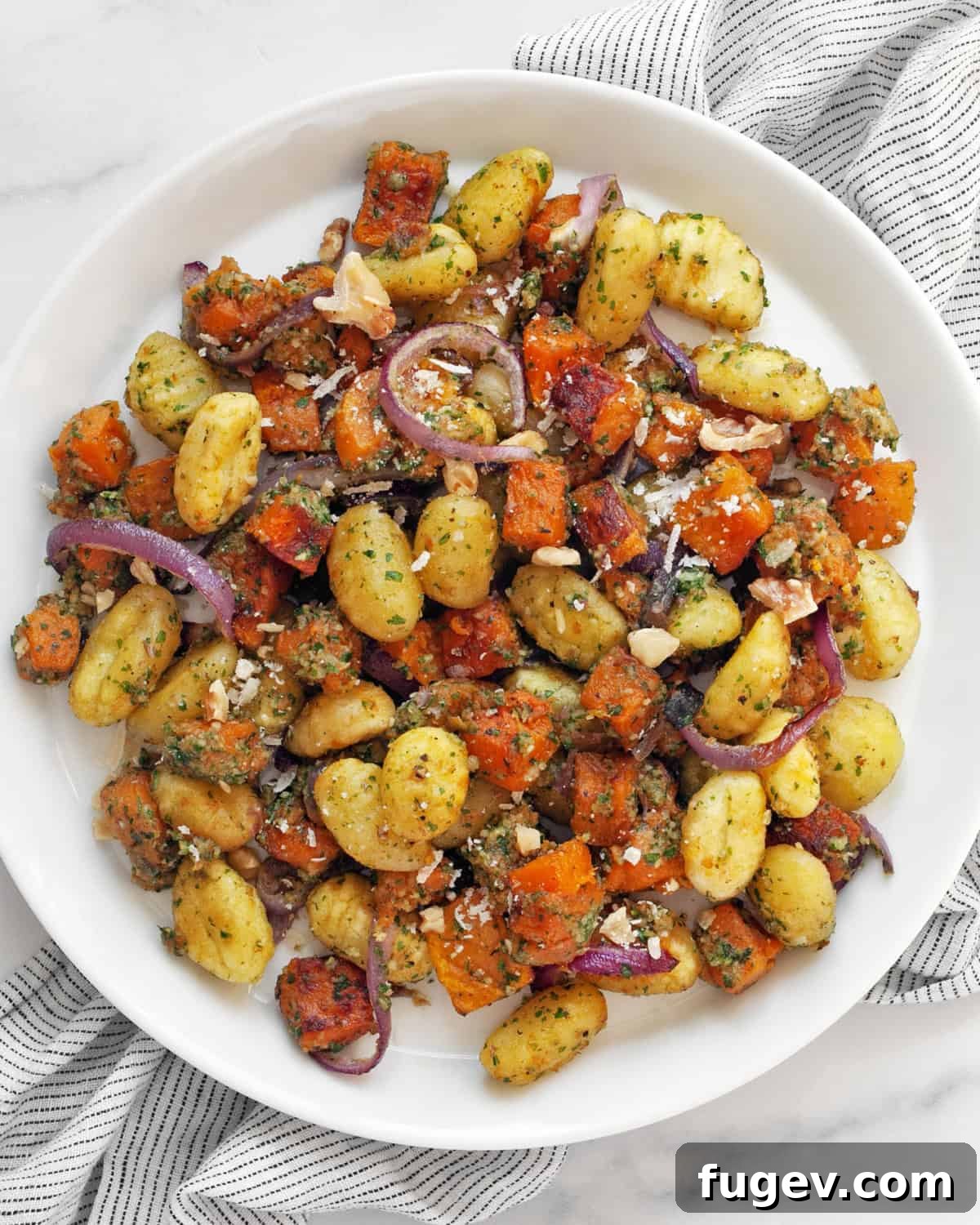 One Pan Butternut Gnocchi with Bright Parsley Pesto 7 A beautifully plated serving of roasted butternut squash sheet pan gnocchi with parsley pesto, garnished with fresh herbs and Parmesan, ready to be eaten.