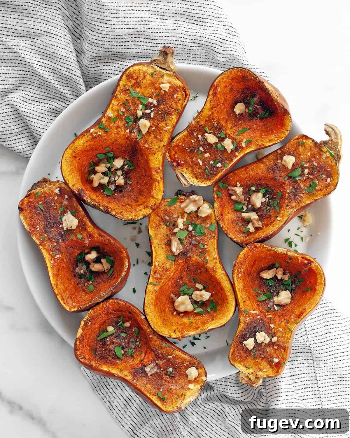 Moroccan Golden Honeynut Roast 7 A close-up shot of Moroccan-spiced roasted honeynut squash on a white plate, highlighting the rich spices and tender, caramelized flesh.