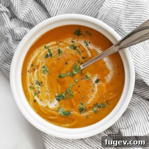 Bowl of vegan roasted kabocha squash soup garnished with fresh herbs.